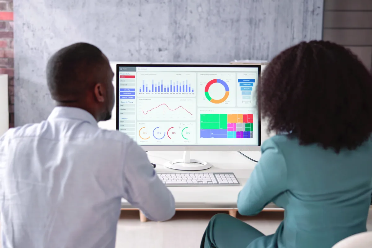 Two marketers reviewing search and AI visibility analytics together on a desktop monitor in a modern office