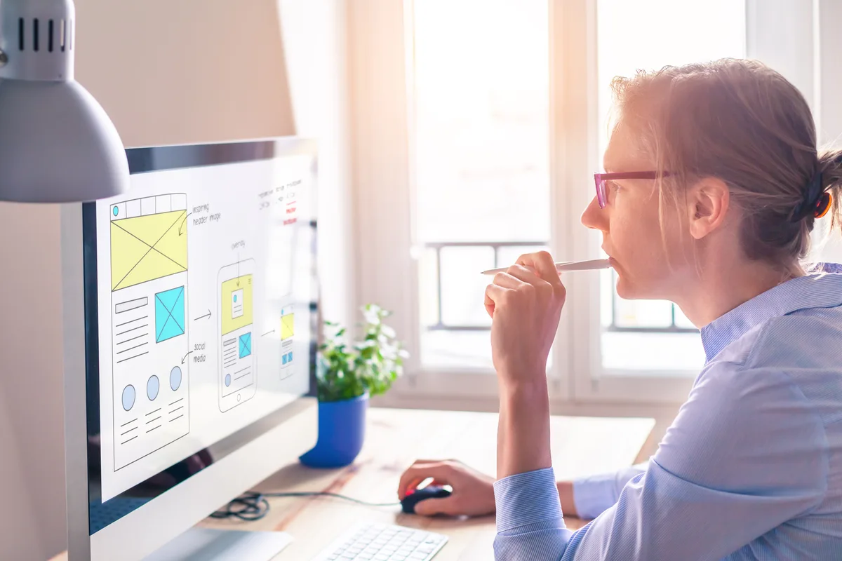 A web strategist reviewing a service landing page wireframe and conversion layout on a desktop monitor