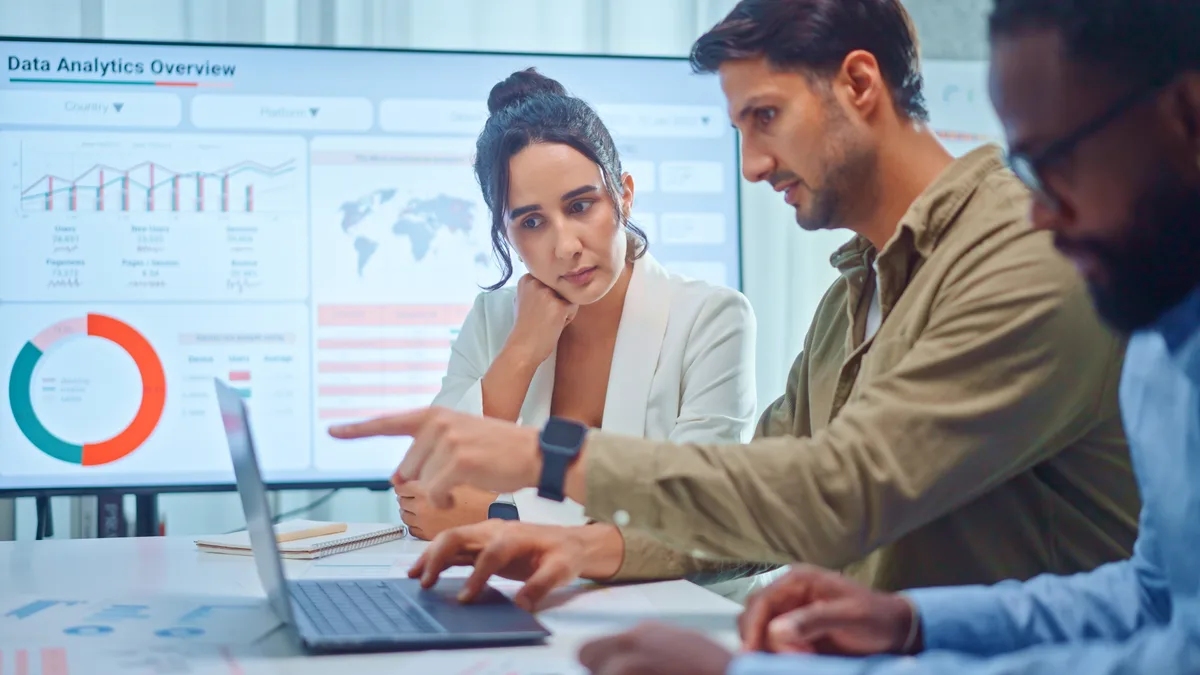 A marketer reviewing email campaign open and click metrics on a laptop dashboard at a desk