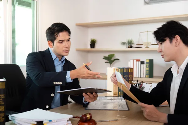 Bankruptcy attorney reviewing debt and financial documents with a client across a desk in a law office