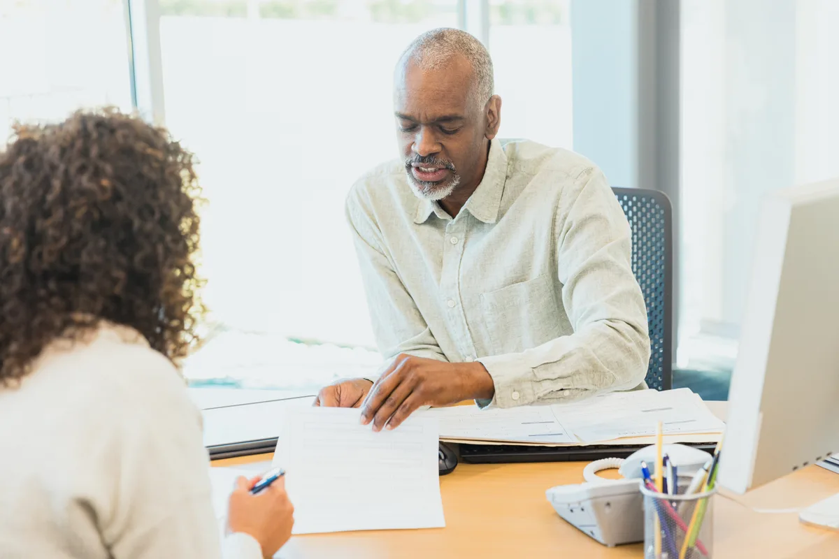 A credit repair specialist reviewing a client's credit report and dispute paperwork across a desk