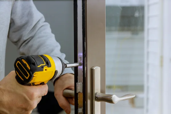 Locksmith fitting a deadbolt at a home's front door during a service call