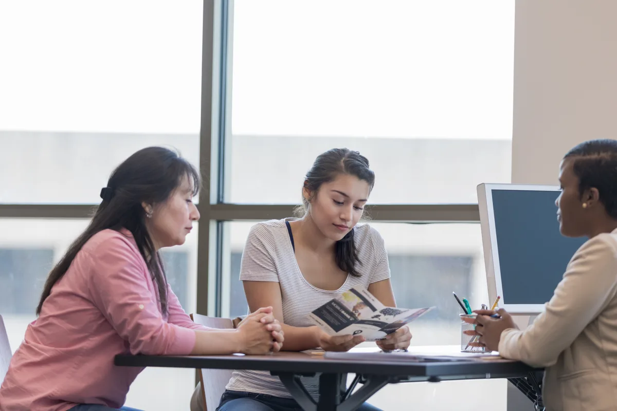 Tutoring center owner reviewing an enrollment plan with a parent at a desk
