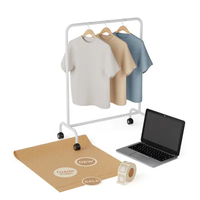 Three boxy tees in cloud white, sand, and harbour blue hanging on a white rolling rack, with kraft wrapping paper and a thank-you sticker roll below