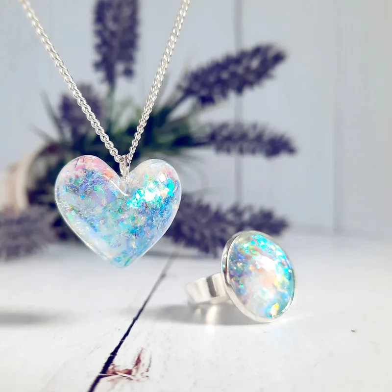 The Éa opal heart pendant and Isla opal ring flashing blue and rose against whitewashed wood