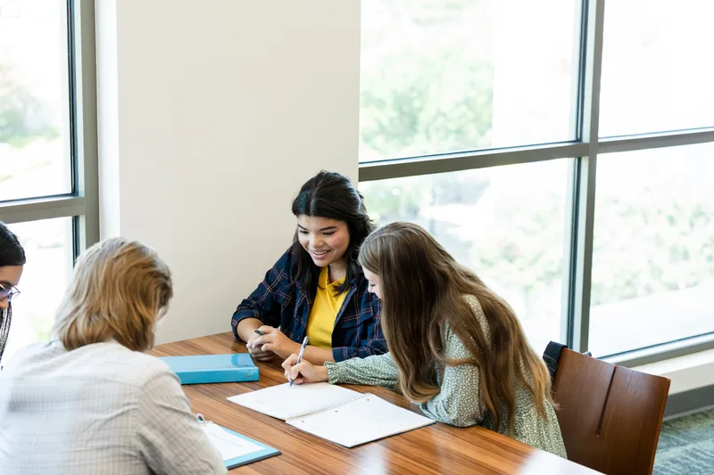 The homework club table by the tall Davis Street windows, students working over open notebooks