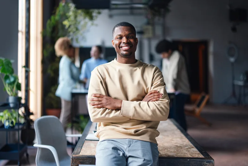 Daniel Reyes, Steadwell client advocate, smiling with arms crossed in a bright, plant-filled office