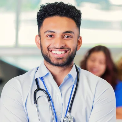 Dr. Mateo Reyes, a family medicine physician with a stethoscope, smiling in a bright clinic