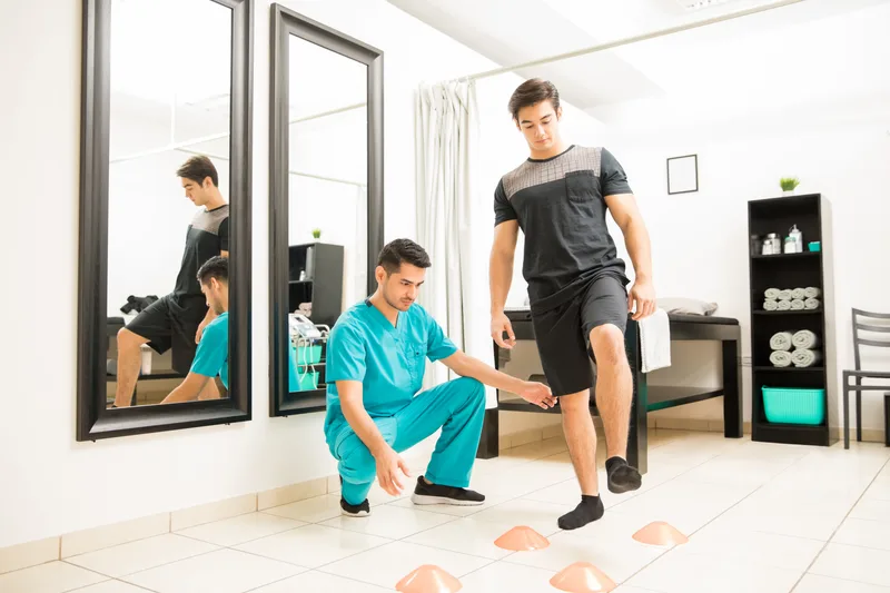 Therapist coaching a patient stepping through agility cones during a rehab session