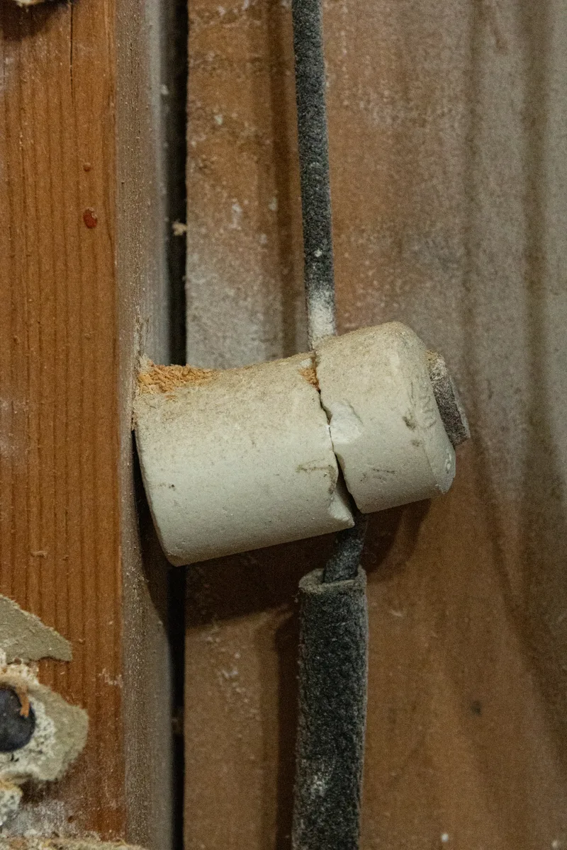 Original knob-and-tube wiring on a ceramic knob inside a century home's wall cavity