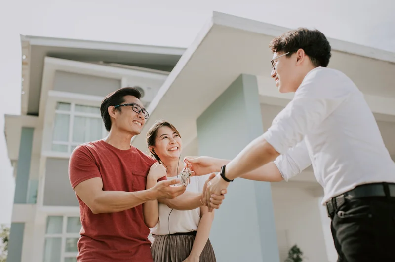 Close-up of a couple signing mortgage documents while an advisor points to the signature line