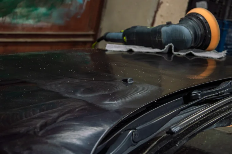 Detailer polishing a car to a high-gloss finish in a detailing shop