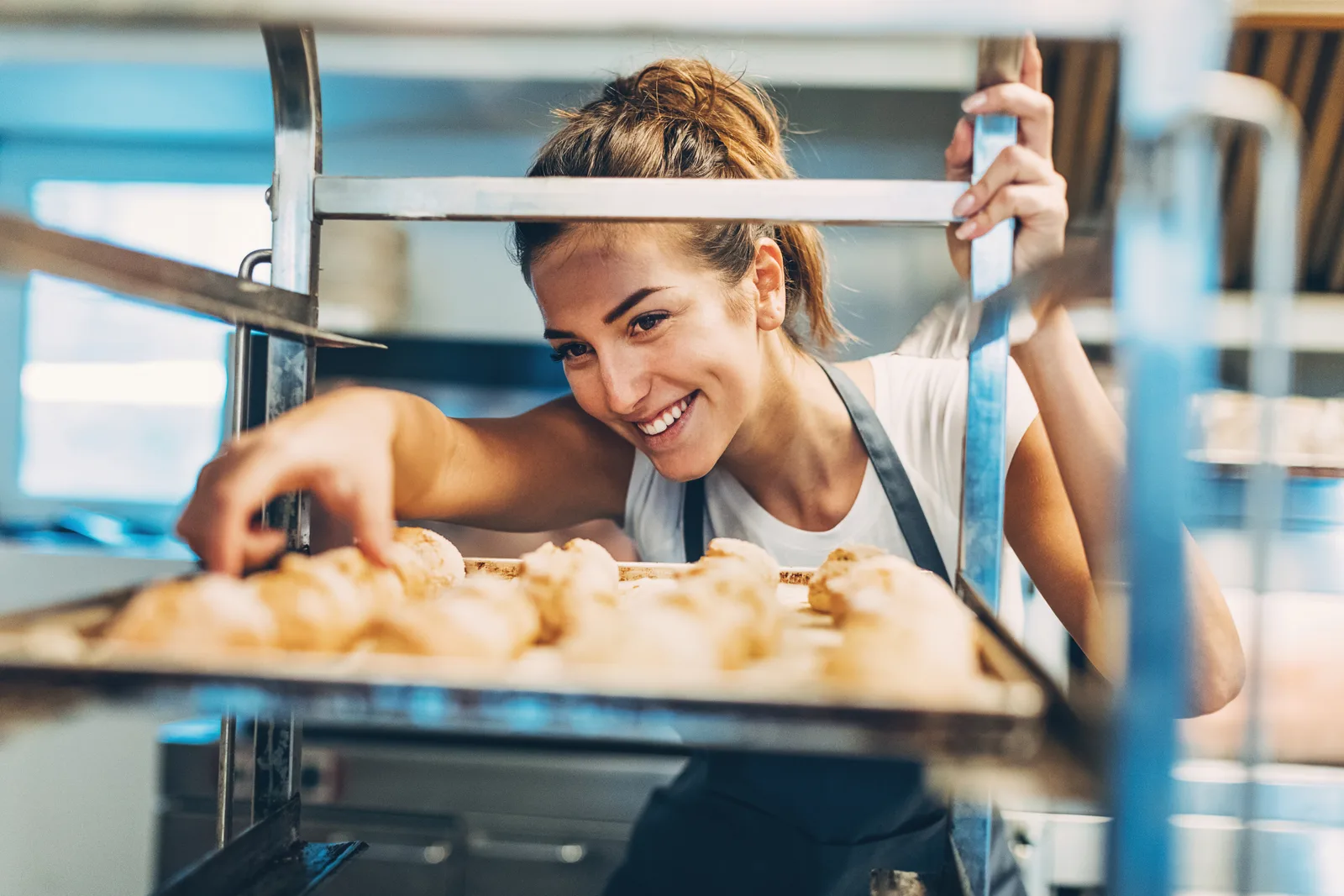 Baker pulling a tray of golden croissants from the oven in a neighborhood bakery