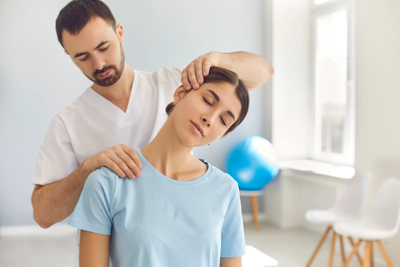 Chiropractor adjusting a patient's neck on a clinic treatment table