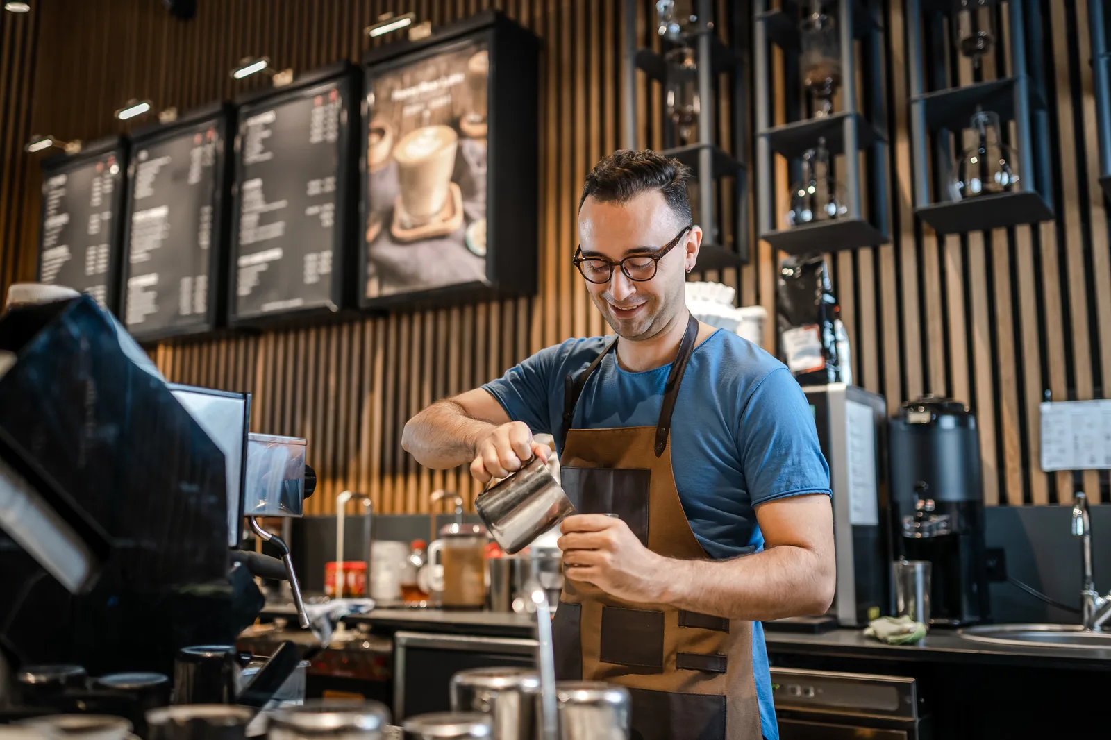 Barista steaming milk at the espresso machine of a busy café counter