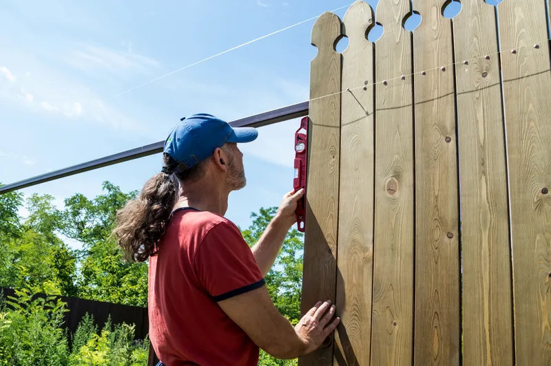 Contractor building a wooden privacy fence in a backyard