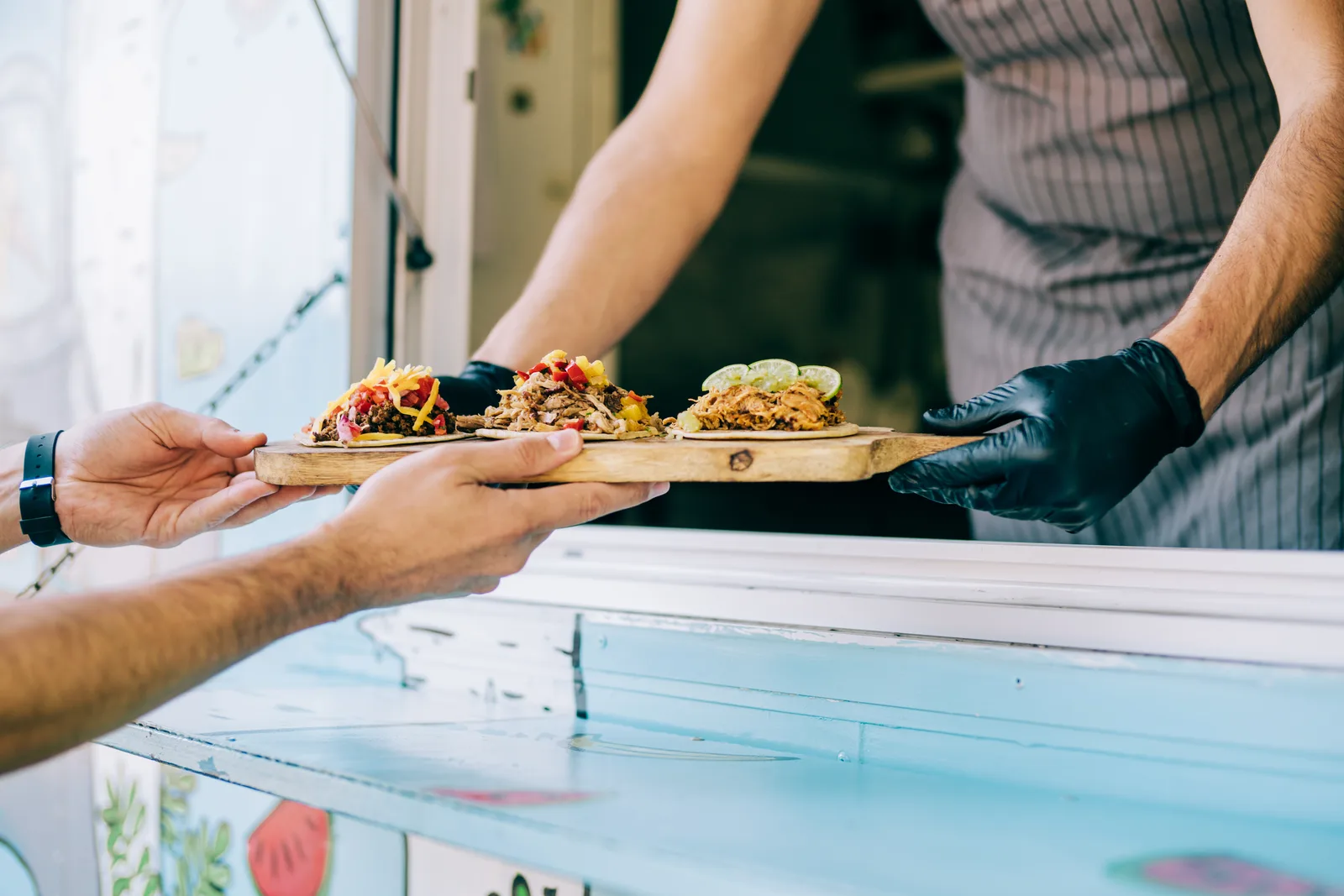 Food truck owner handing an order to a customer at the service window during a lunch stop