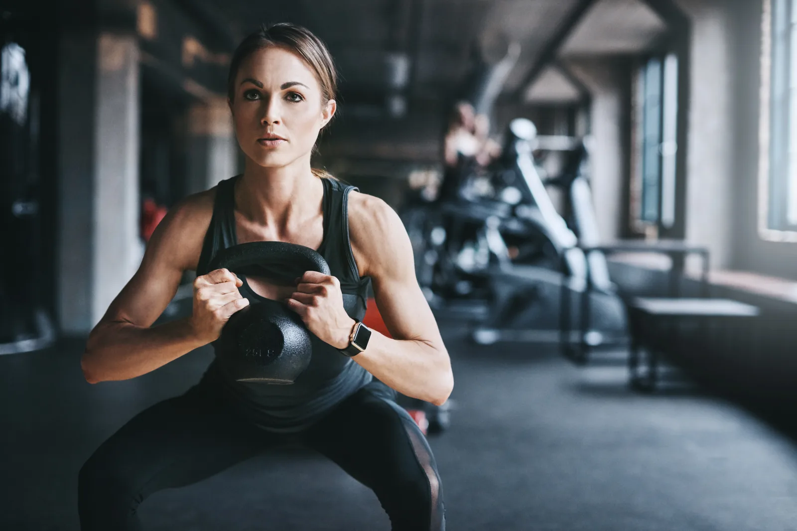 Gym members lifting weights side by side on their club's strength floor