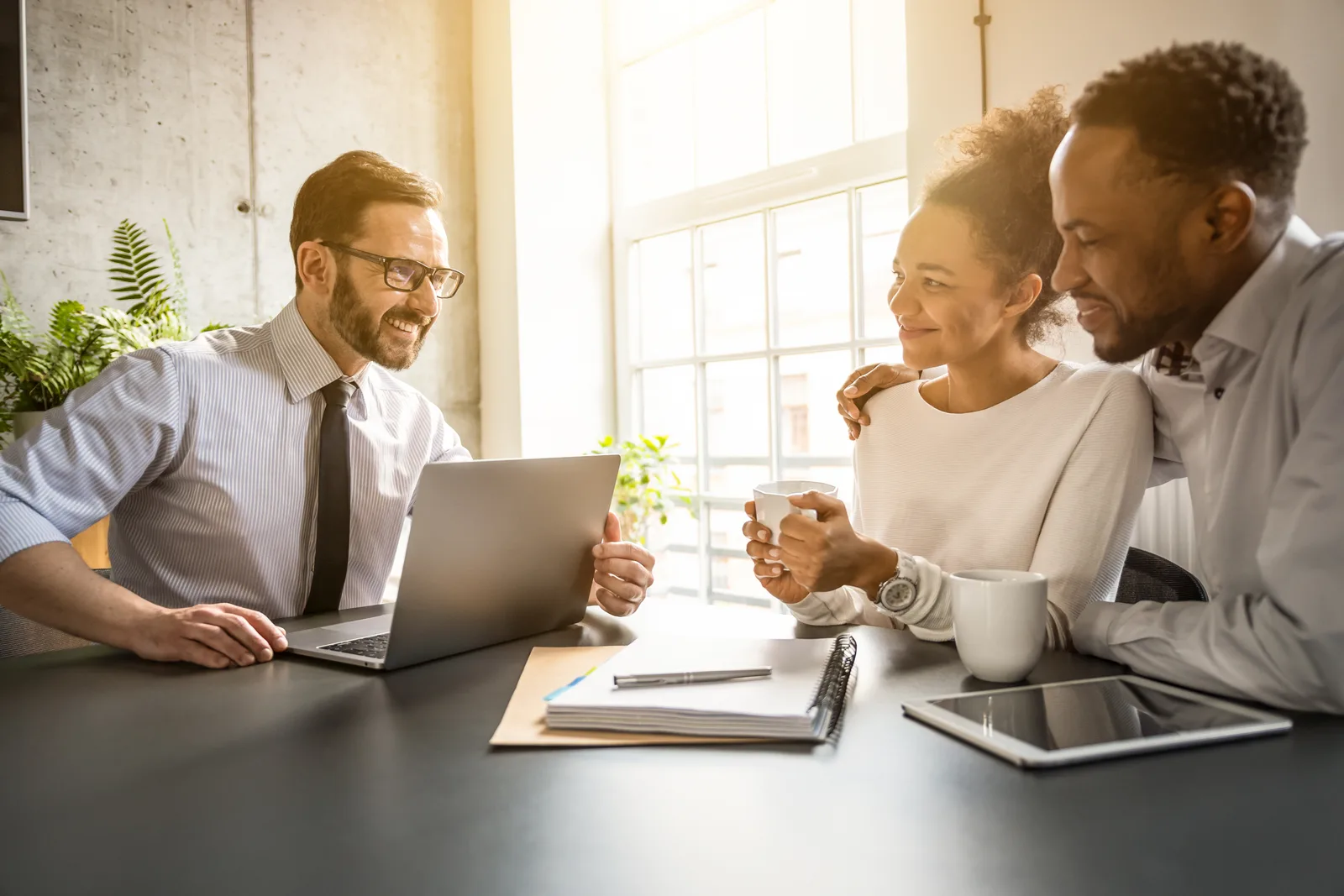Independent insurance agent walking a young couple through auto and home coverage options at her desk