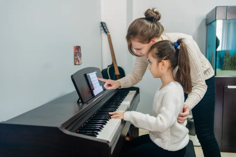 Music teacher giving a child a piano lesson