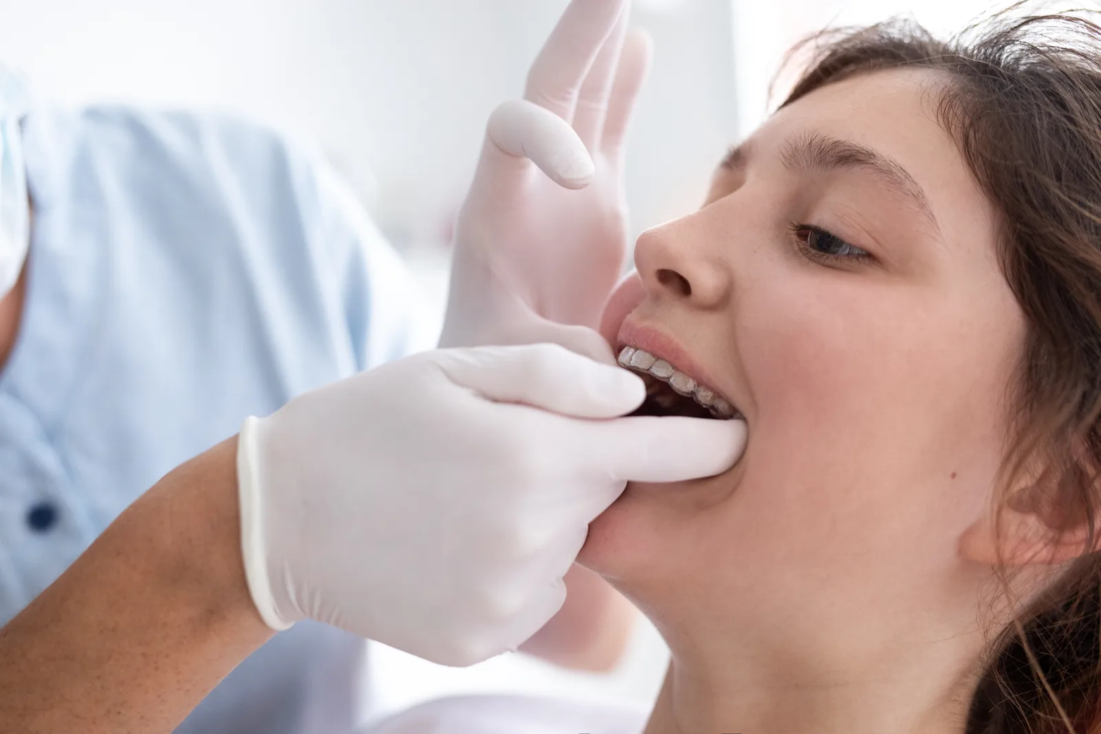 Orthodontist showing a teenage patient her braces and clear-aligner options chairside during a consultation