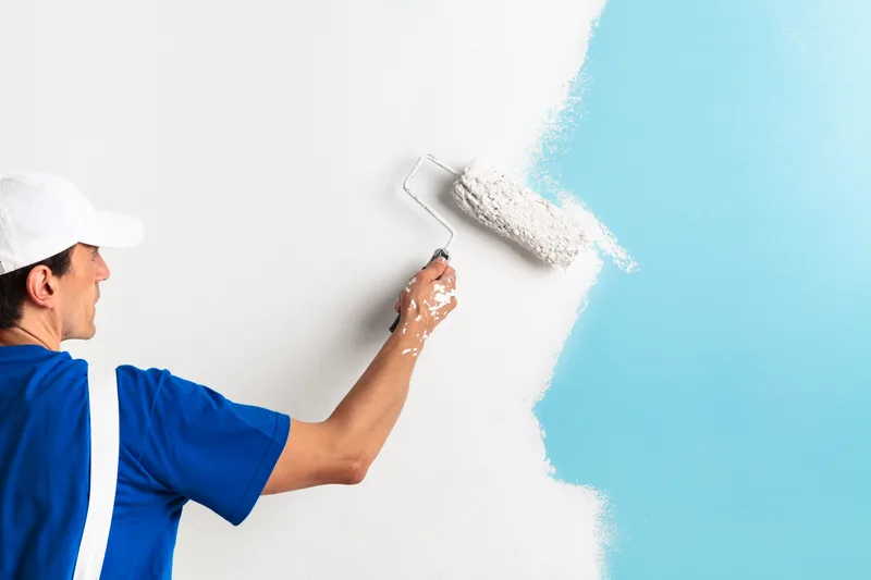 Professional painter applying paint to an interior wall with a roller