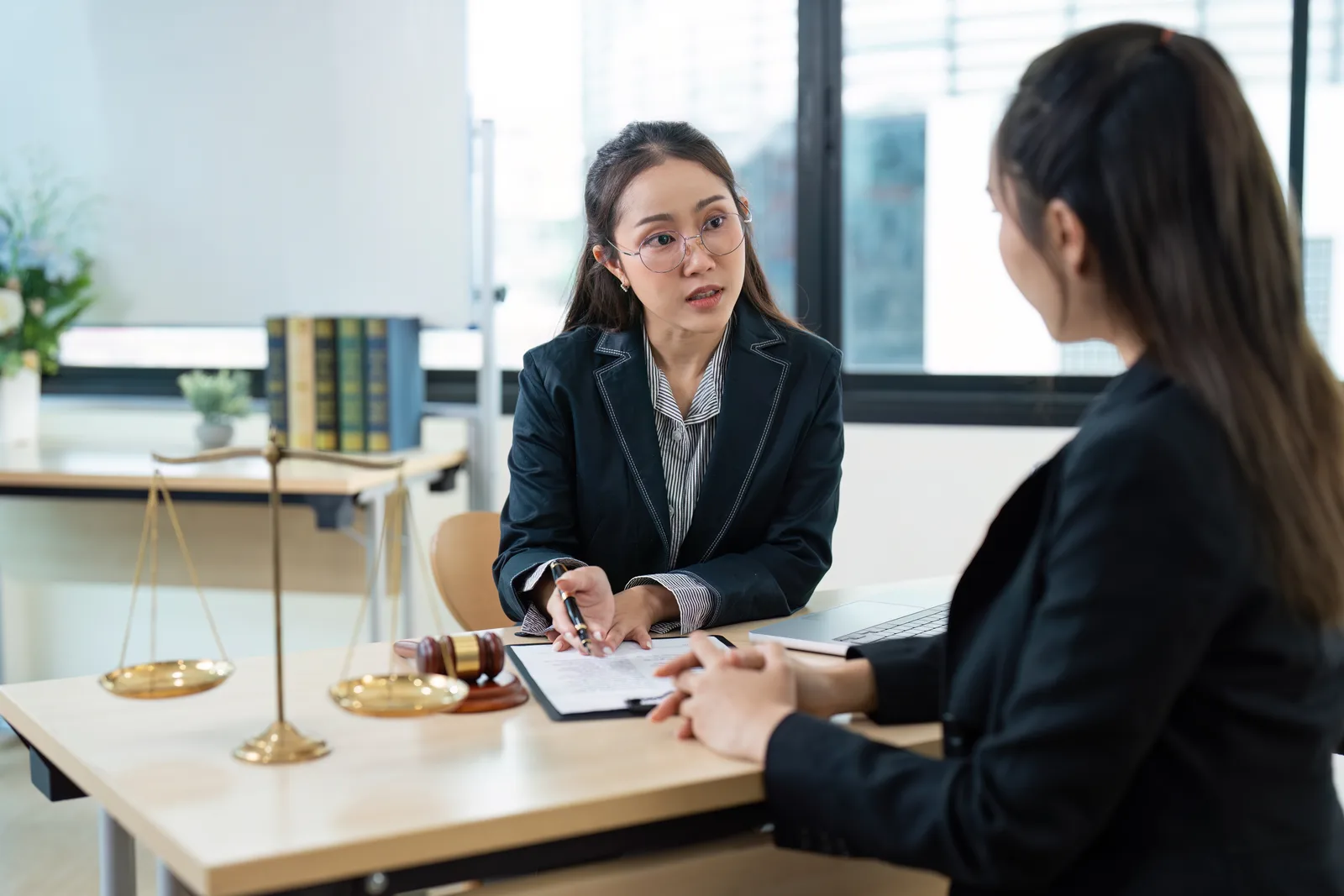 Personal injury lawyer reviewing accident photos and medical records with an injured client at a law office conference table