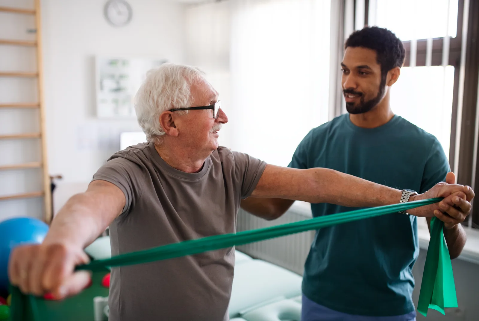 A physical therapist coaches a patient through a rehab exercise on the clinic treatment floor