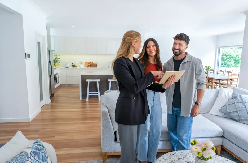Real estate agent showing a modern home to a happy couple
