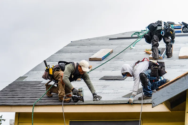Roofing crew installing shingles on a residential roof