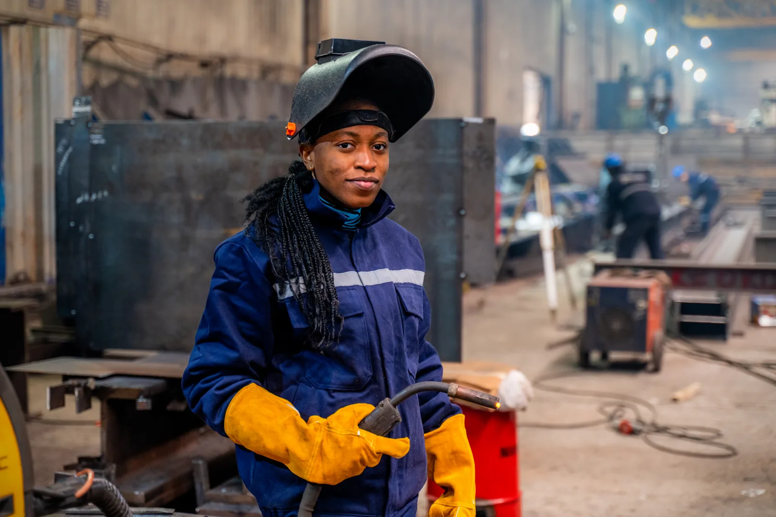 Trade school student in a welding helmet practicing welds in the shop lab