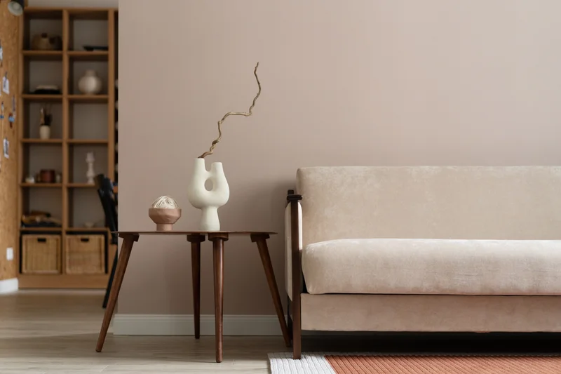 Staged living room of suite 808 with a cream boucle sofa, walnut side tables and blush-toned walls