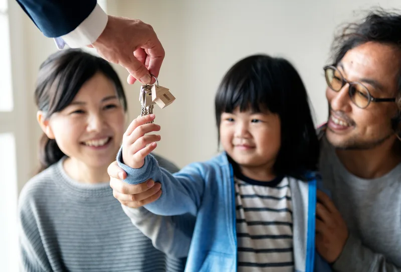 A Cardinal agent handing house keys to a delighted young family on closing day