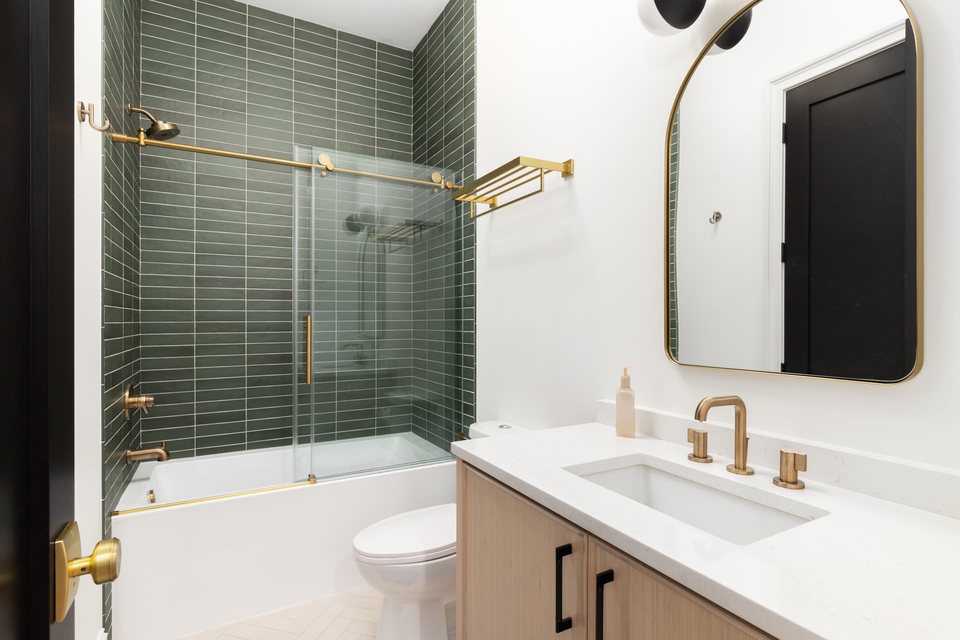 Meridian palette secondary bath: sage-green stacked tile in the shower, brass rail and fittings, and a white-oak vanity — artist's impression.