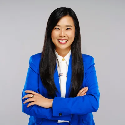 Studio portrait of Grace Yoon, owner of Yoon Electric, arms crossed in a bright blue blazer